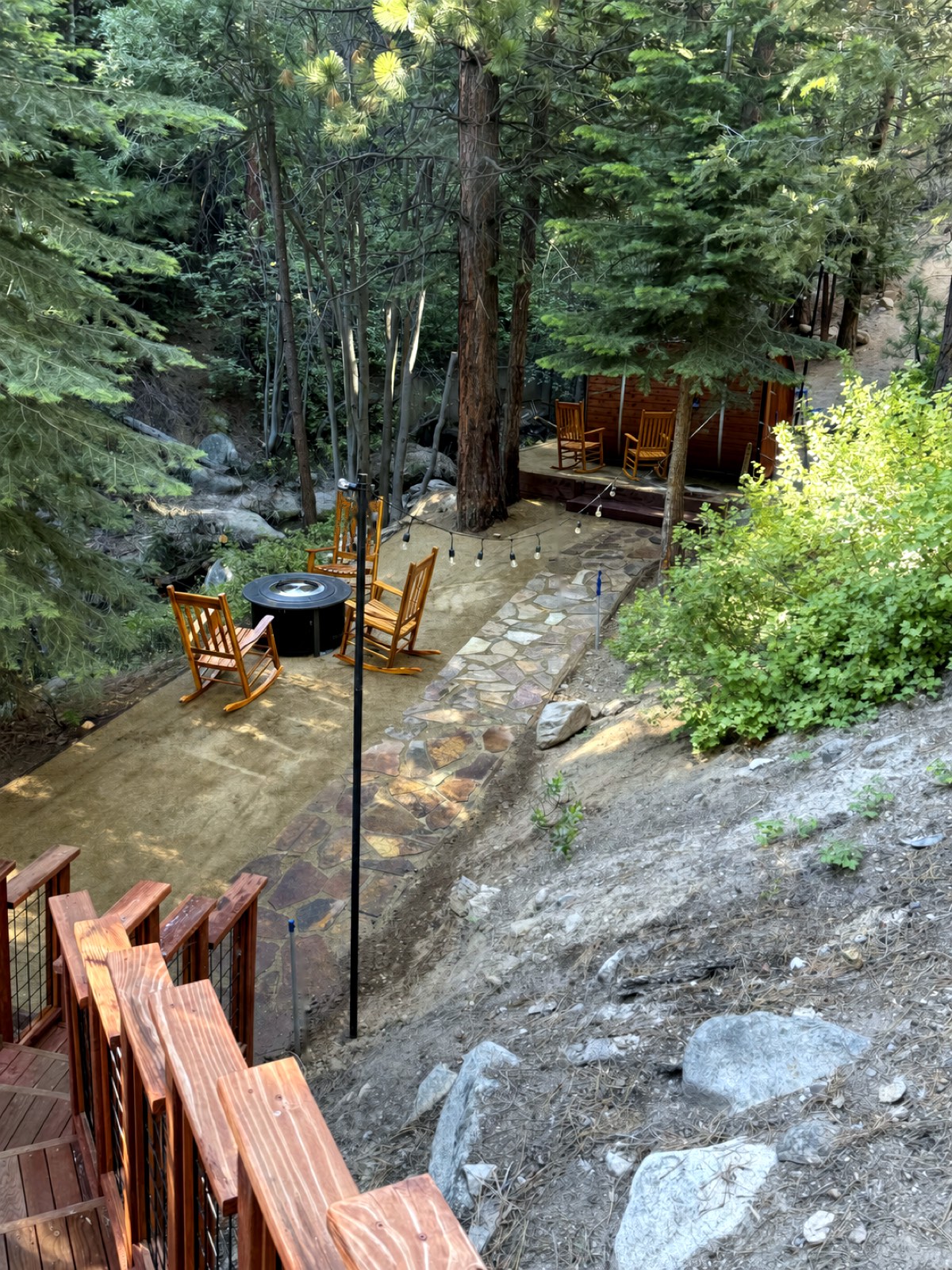 Aerial view of the fire-pit patio, flagstone path and sauna set among the trees along the creek
